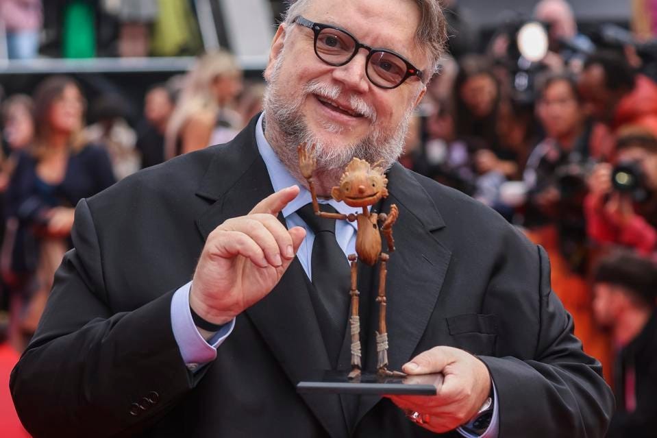 Guillermo Del Toro holding a Pinocchio figurine.