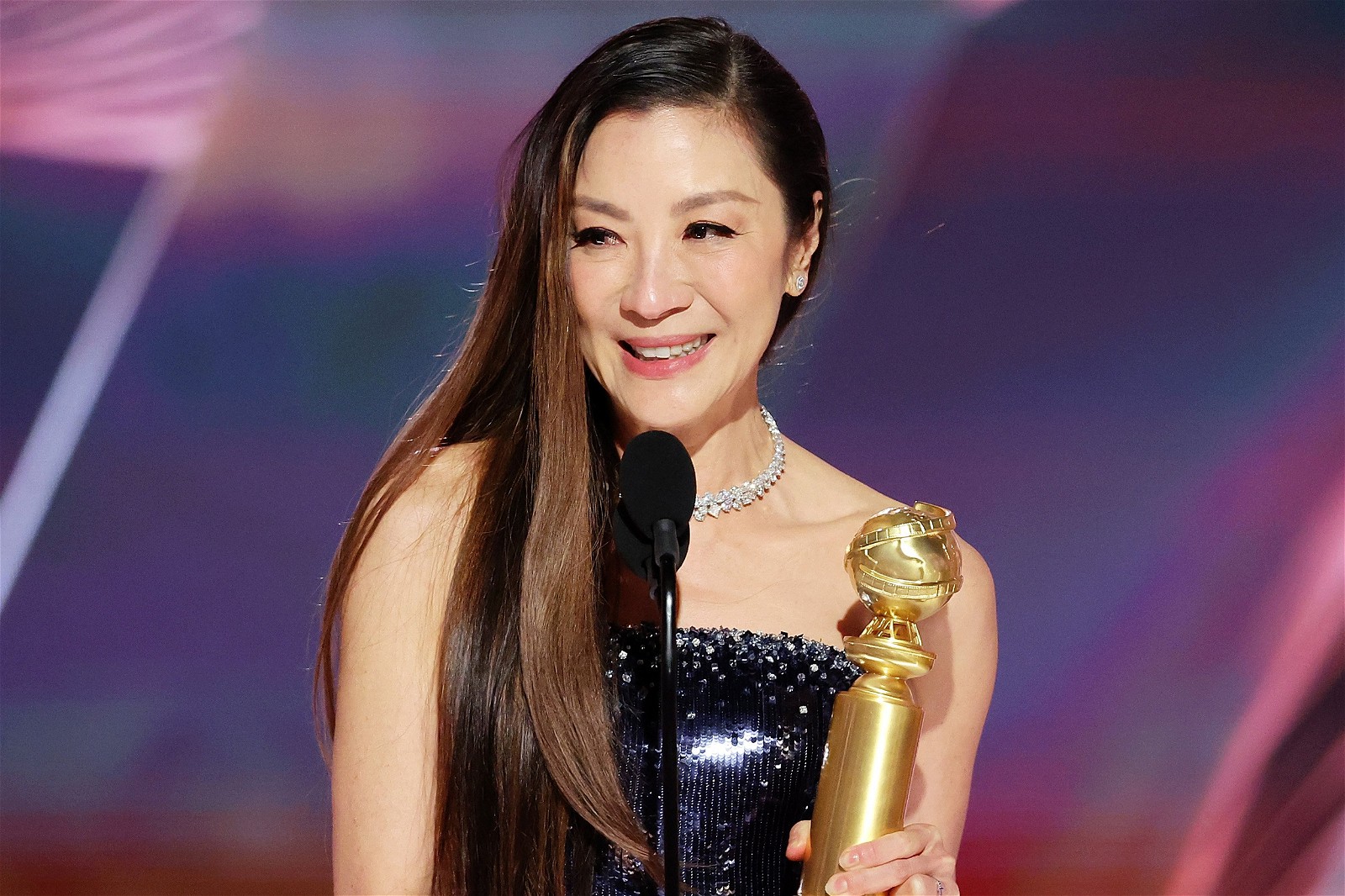 Michelle Yeoh holding a Golden Globe award.