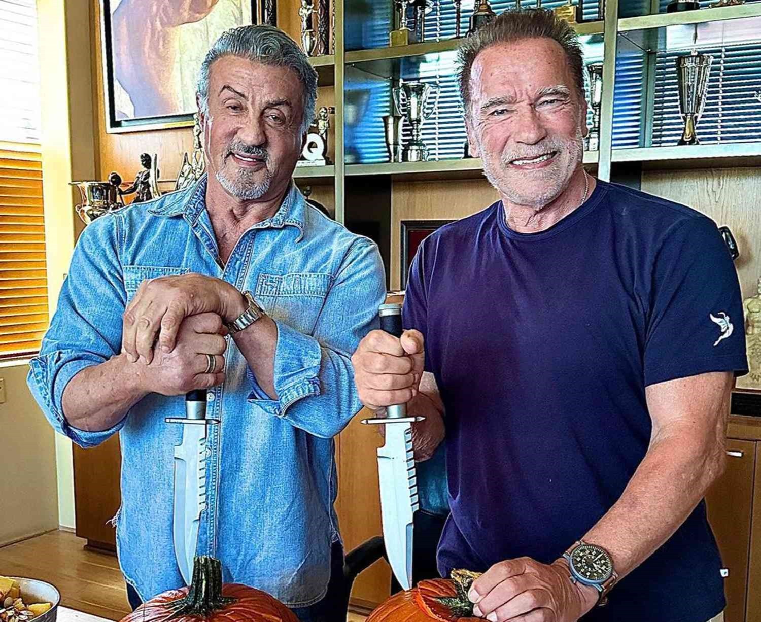 Arnold Schwarzenegger and Sylvester Stallone carving pumpkins.