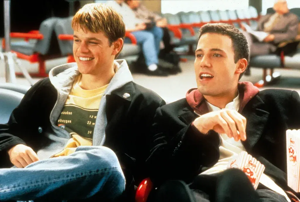 Matt Damon and Ben Affleck sitting and laughing while eating popcorn in Dogma.