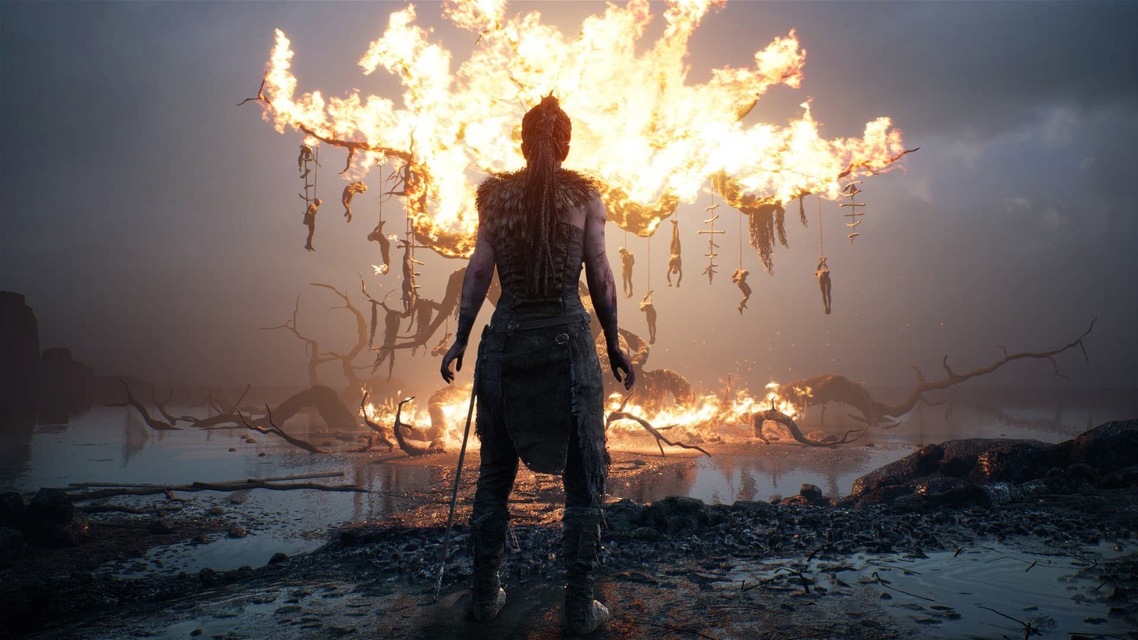 A still of the character looking at a burning tree in-game