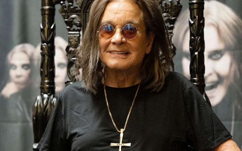 Ozzy Osbourne is sitting on his throne while smiling 