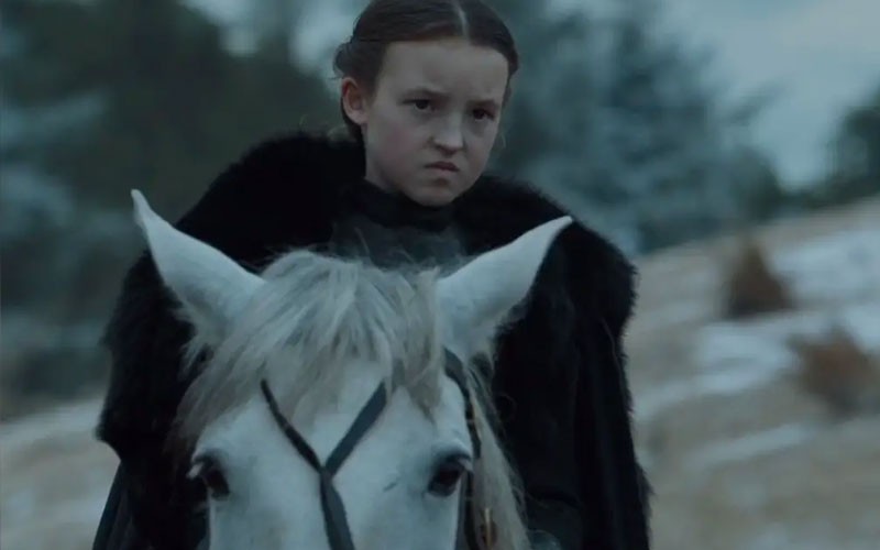 Bella Ramsey showing an angered expression while riding horseback 