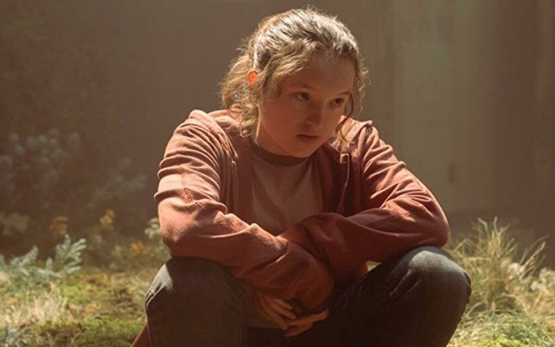 Bella Ramsey sitting on the ground as Ellie in The Last of Us 