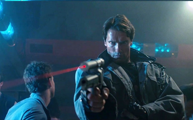 Arnold Schwarzenegger pointing a gun with infrared laser in this scene 
