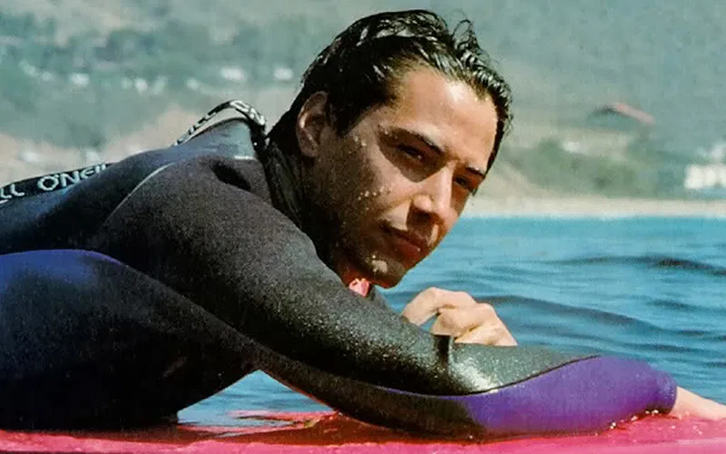 keanu reeves surfing in a still from point break.