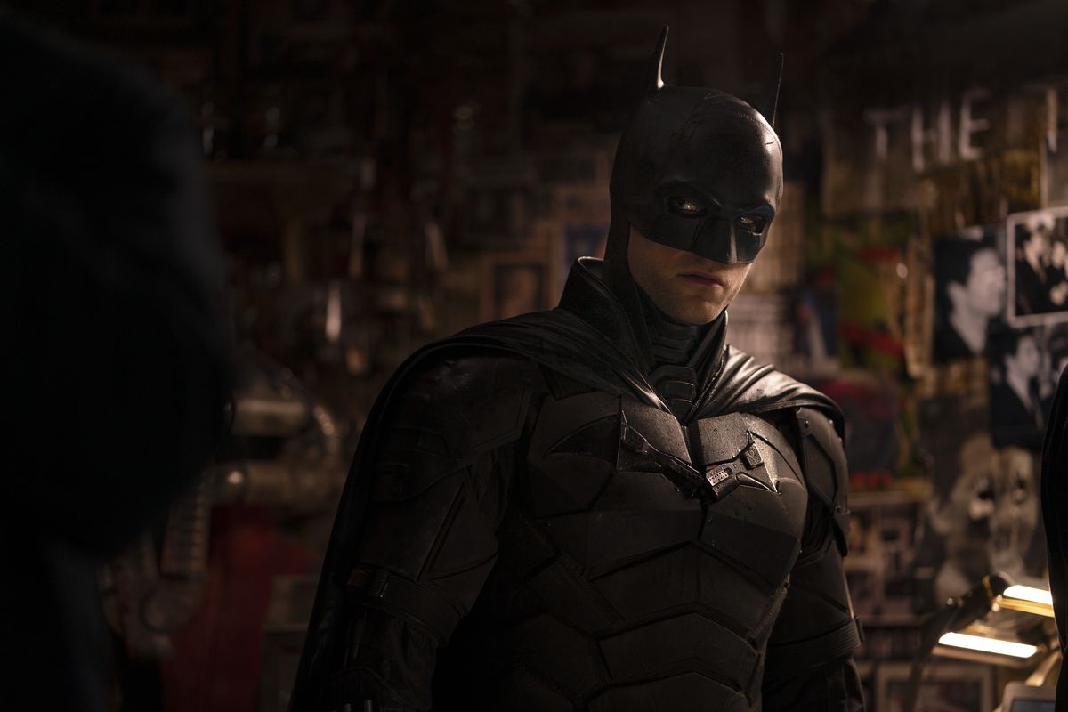 Robert Pattinson as Batman at a crime scene in a still from The Batman
