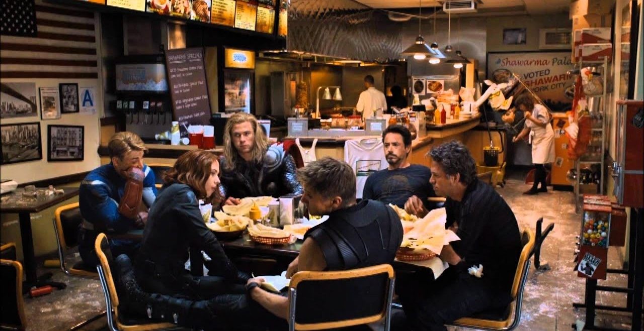 the six avengers sit around a table in silence eating shawarma in The Avengers