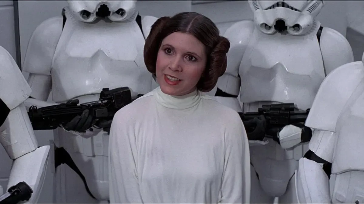 Carrie Fisher is surrounded by stormtroopers in a scene from Star Wars: A New Hope