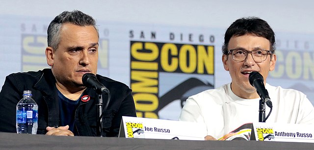 The Russo Brothers sitting at a comic con panel discussing their works.