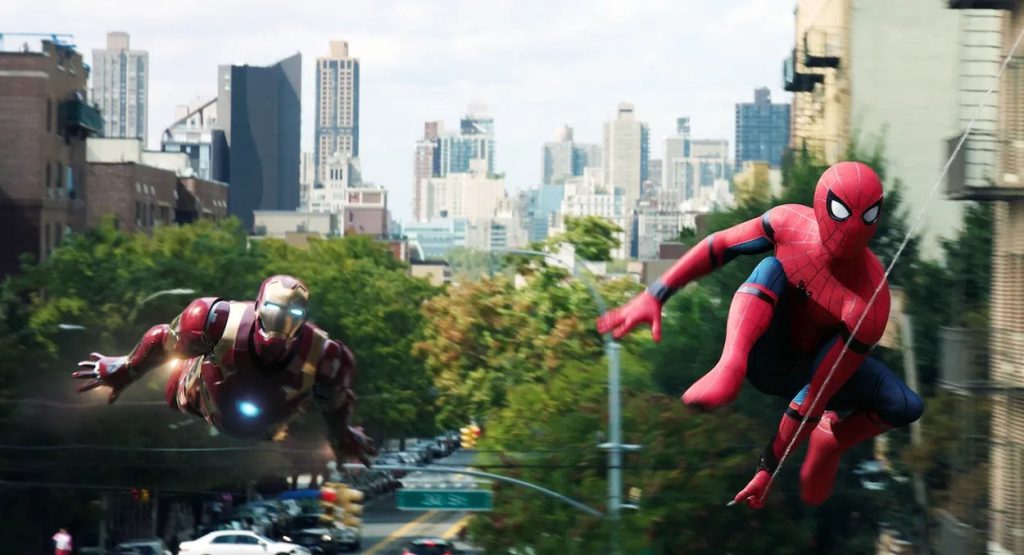 Tom Holland as Spider-Man swinging by and Robert Downey Jr. as Iron Man in an official still from Spider-Man: Homecoming