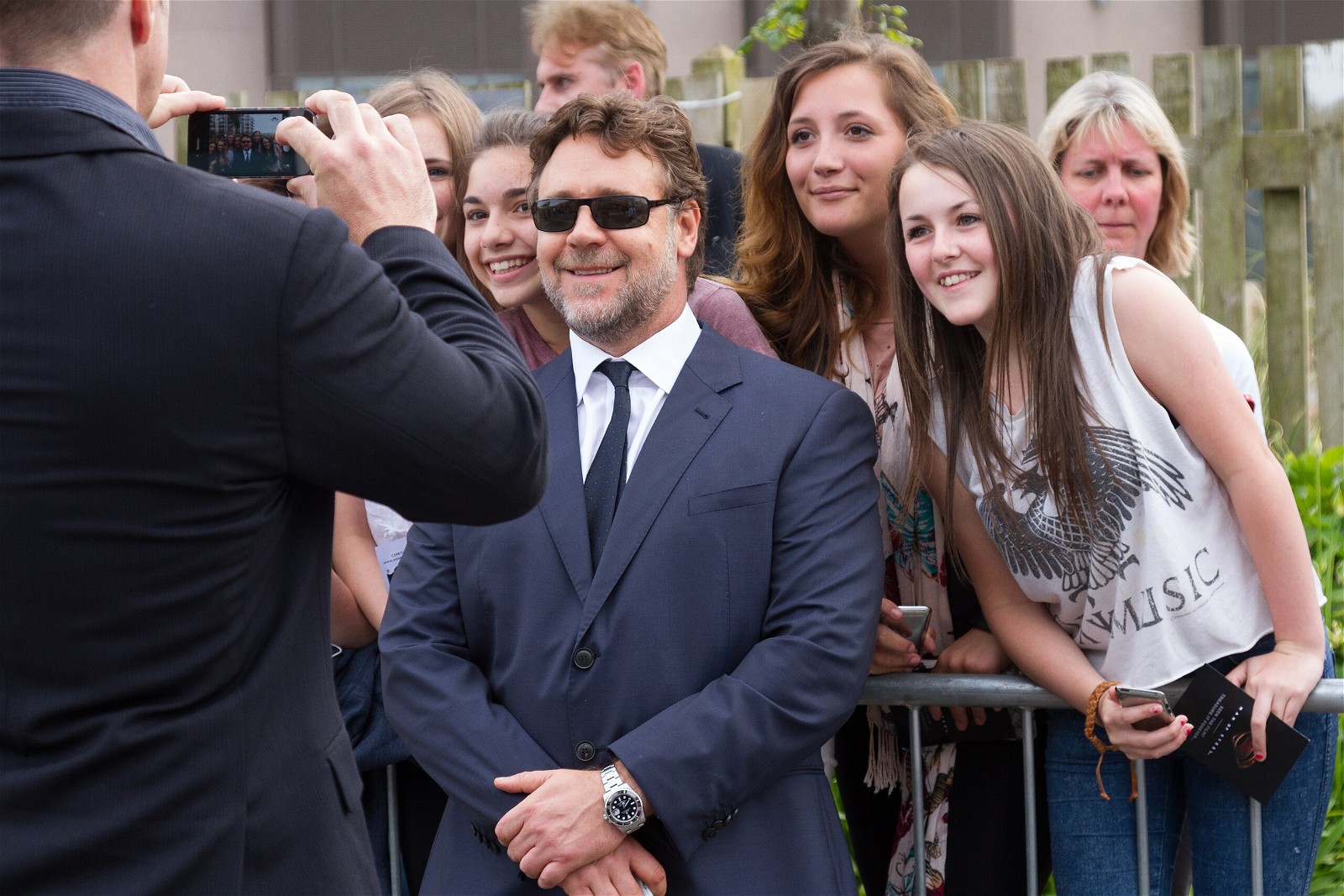 Russell Crowe smiling while posing with fans in St Helier