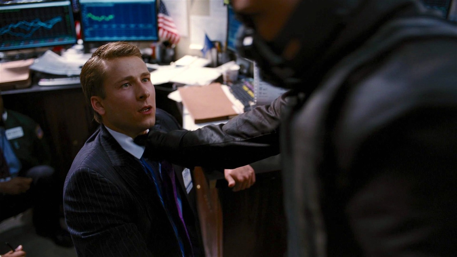 Glen Powell plays a trader in a scene from The Dark Knight Rises