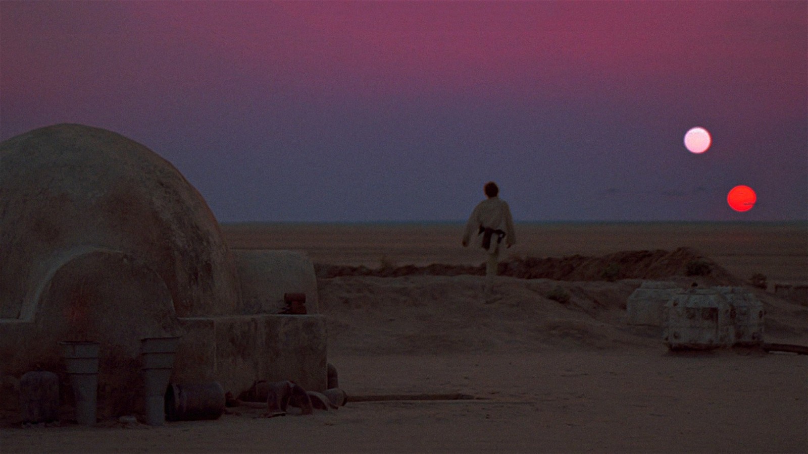 A still featuring Luke Skywalker walking across a double sunset in Star Wars (1977) by George Lucas