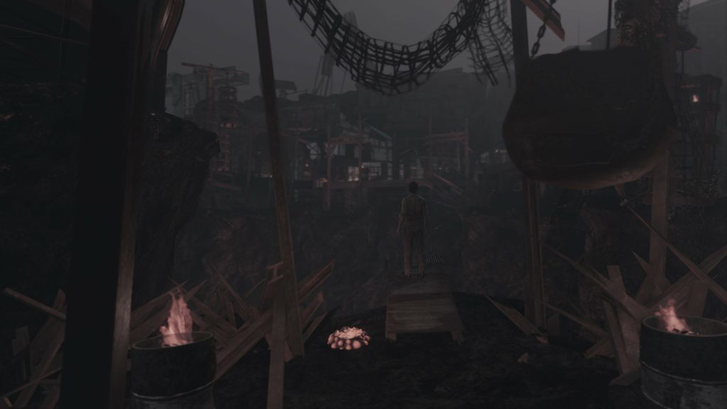 A location in Fallout London with a character standing atop a wooden platform overlooking a massive cluttered space.