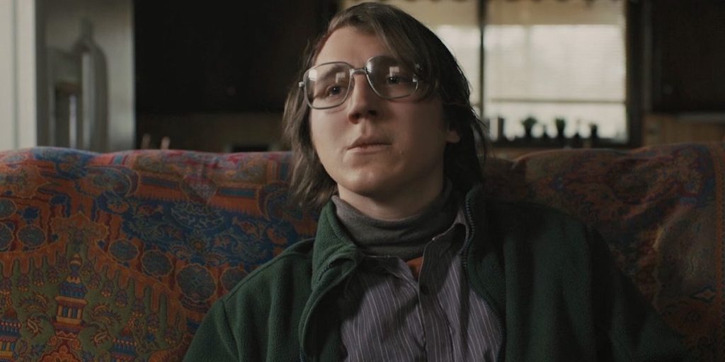 Paul Dano in a still from The Batman sitting on a couch.