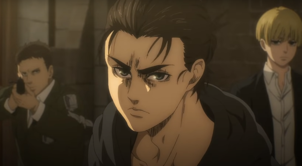 Eren looks on aggressively with two people in the background who appear blurred in Attack on Titan