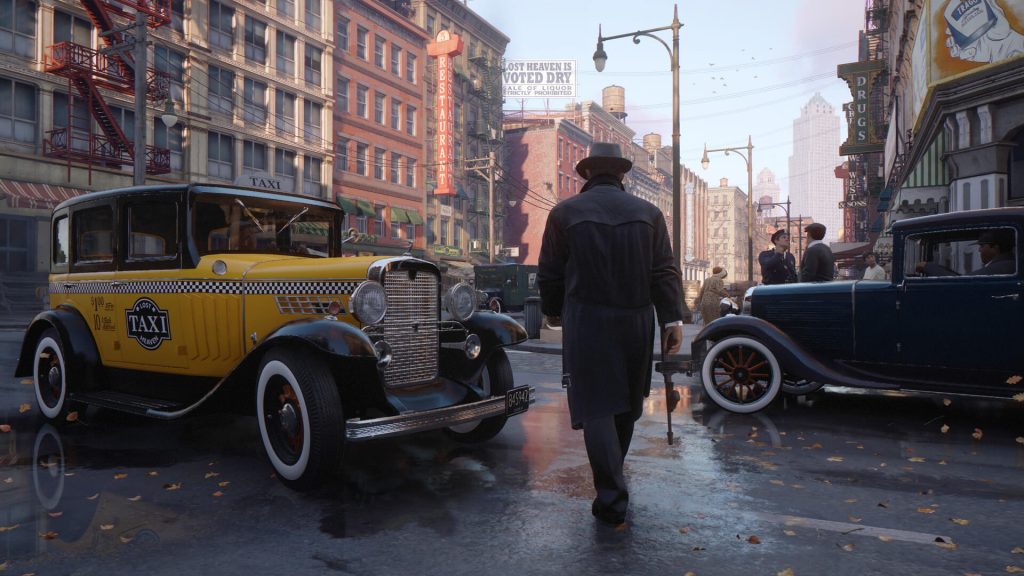 The image shows the player with a gun crossing the street in Mafia Definitive Edition 