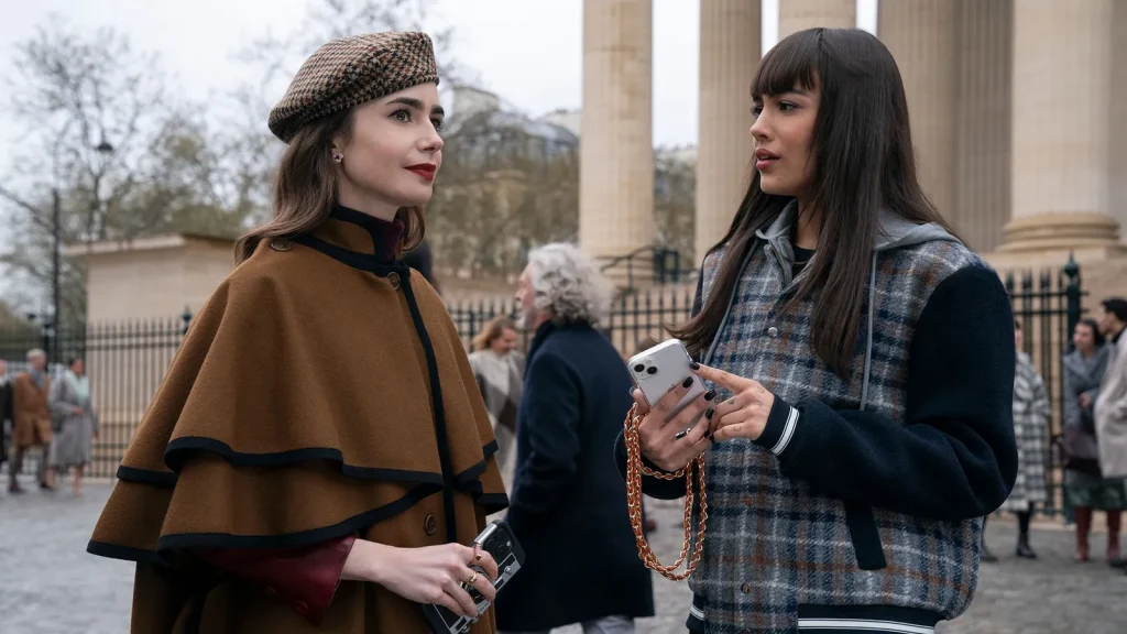 Thalia Besson as Genevieve and Lily Collins as and in Emily in Paris. 