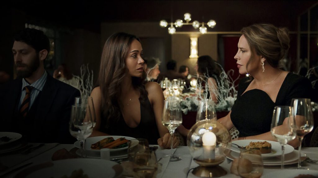 Zoe Saldaña and Karla Sofía Gascón in a restaurant scene from Emilia Pérez.