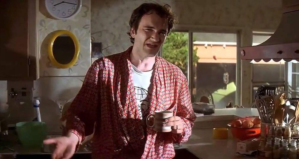 Quentin Tarantino Declares His Favorite 1950 Western Director, and It’s Not Philip Ford 2 Quentin Tarantino in a night suit, holding a cup of coffee and talking in a still from Pulp Fiction.
