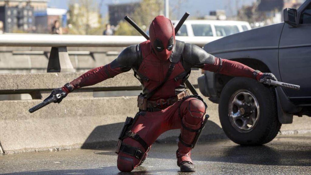 Ryan Reynolds as Deadpool, posing with two guns. 