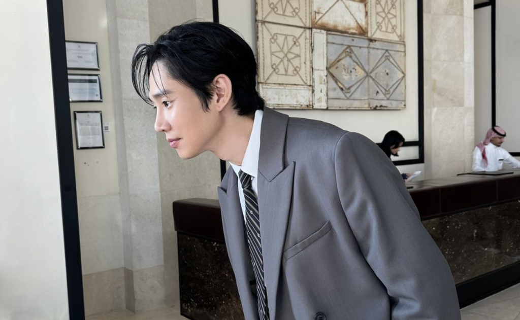 Park Sung Hoon leaning forward in a gray suit and stripped tie. 