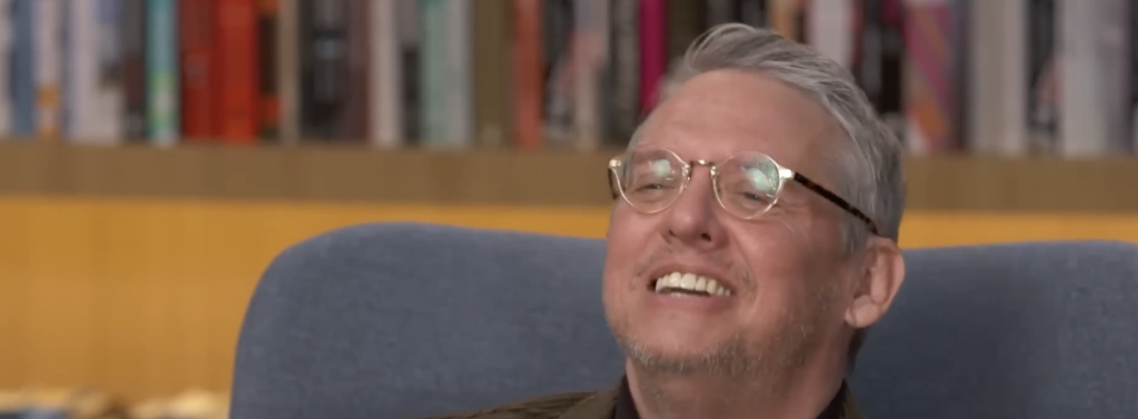 Adam McKay smiling during an interview. 