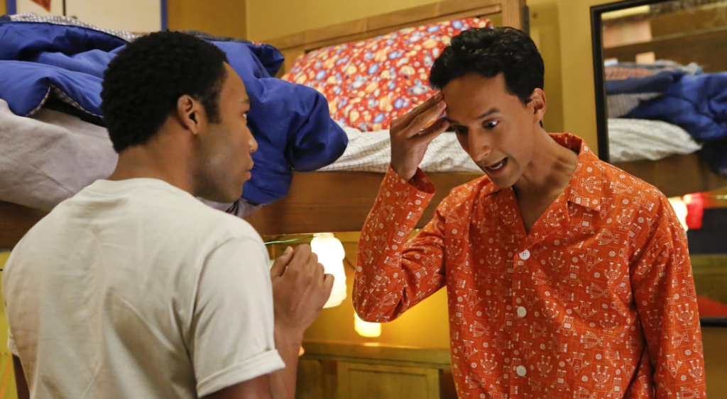 Danny Pudi as Abed Nadir and Donald Glover as Troy Barnes in Community show, engaged in a heated argument. 