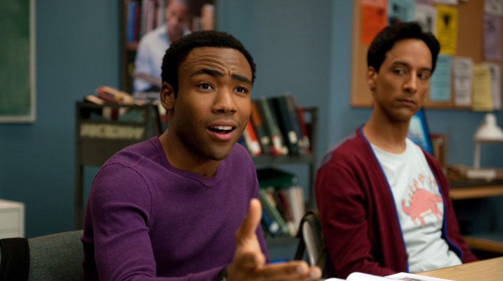 Abed looks thoughtful in the class while Troy listens intently, displaying his usual laid-back demeanor.