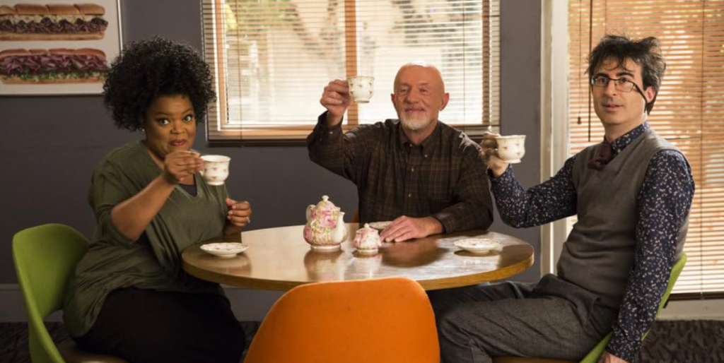 Jonathan Banks, John Oliver, and Yvette Nicole Brown in a lighthearted moment, sitting together and drinking tea.