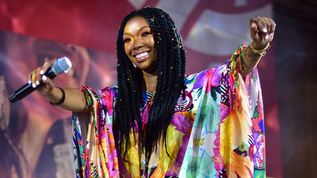 American singer and actress Brandy Norwood in the midst of a performance, smiling.