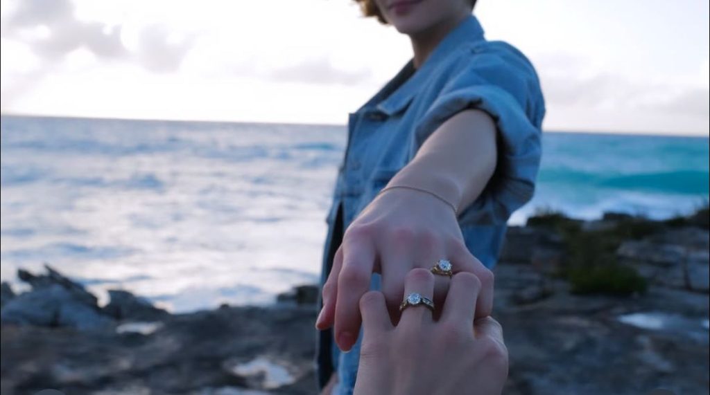 Kate Harrison’s hand holding Chloë Grace Moretz’s, with both wearing rings, likely suggests they are engaged