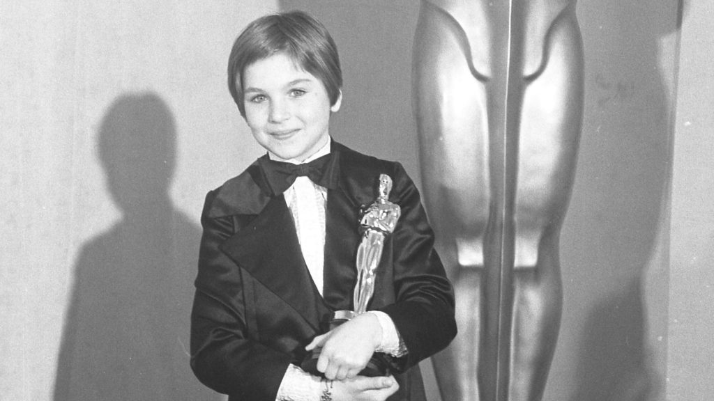 A black and white picture of Tatum O'Neal as a child, holding her Oscar for "Paper Moon," at the 46th Annual Academy Awards.