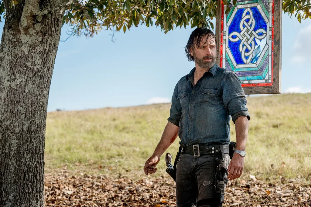 Andrew Lincoln stands next to a tree, looking in anticipation 