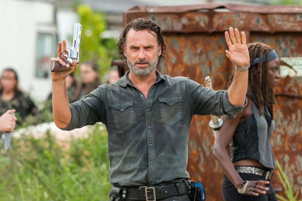 Andrew Lincoln raises his hands and pistol 