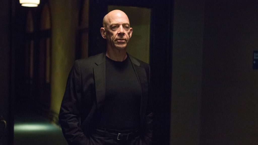 J.K. Simmons in suit, standing in a dim-lit room, in Whiplash