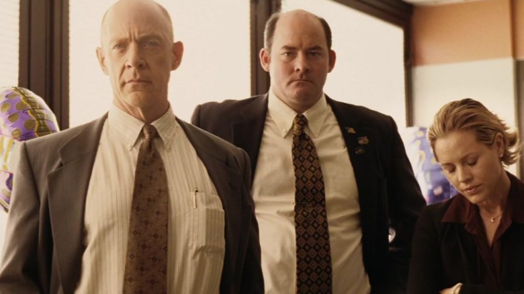 J.K. Simmons, David Koechner standing firmly while Maria Bello looks disappointed