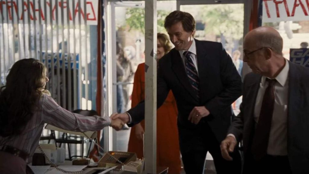 Hugh Jackman shaking hand with a lady while J.K. Simmons waits for him in The Front Runner