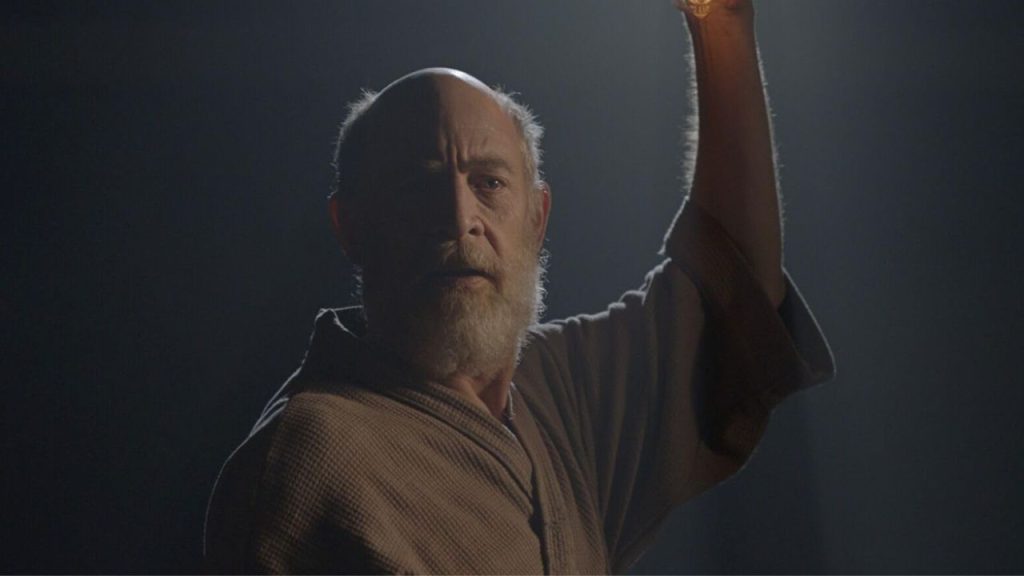 J.K. Simmons looking surprised holding a light in I'm Not Here