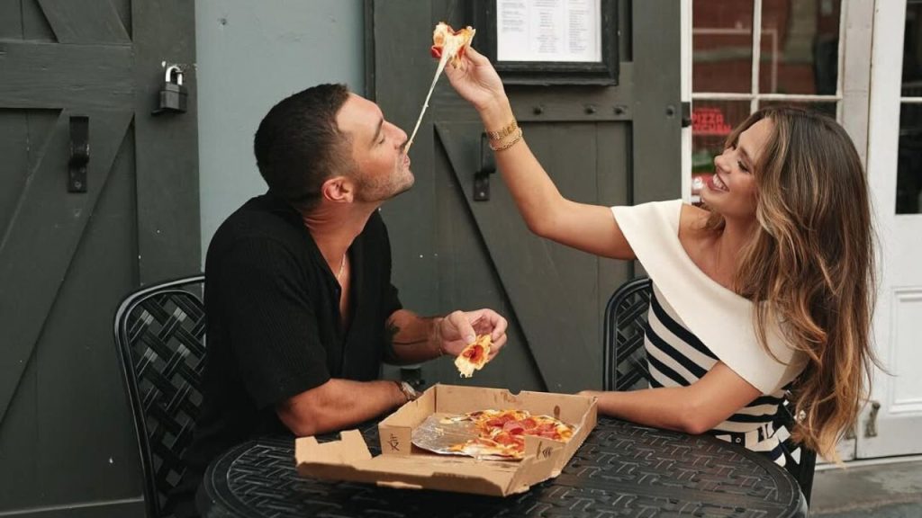 Kelsey Anderson feeding pizza to Joey Graziadei 