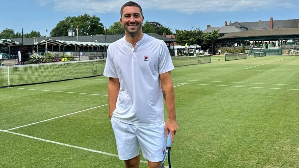 Joey Graziadei posing for a picture holding a tennis racket on court