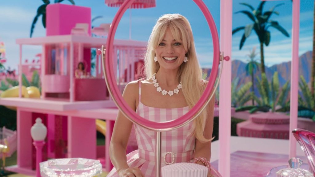 Margot Robbie as Barbie wearing a pink dress in a pink set in Barbie