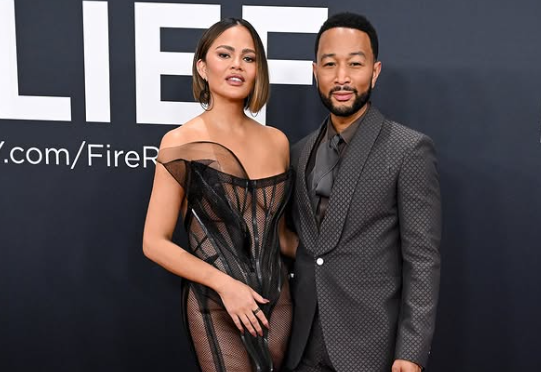 Chrissy Teigen with husband John Legend at Grammy 2025, both wearing black.