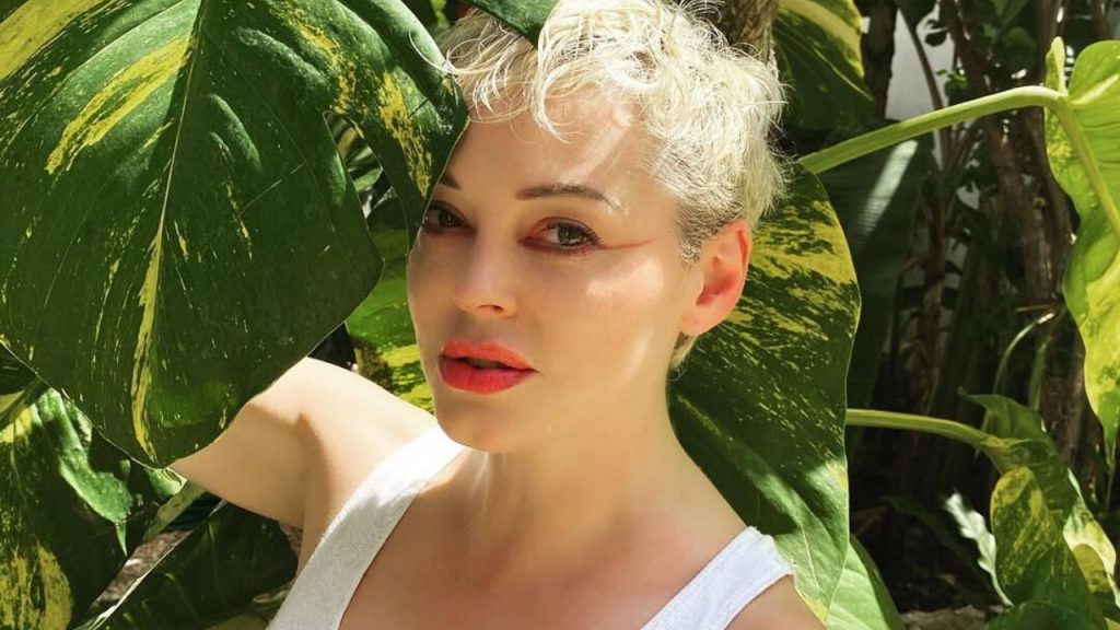 Rose McGowan standing beside a plant, posing for a picture