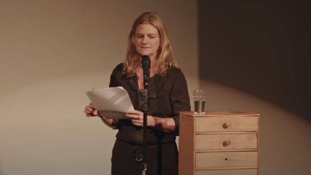 Zelda Perkins holding a script while giving a speech on stage