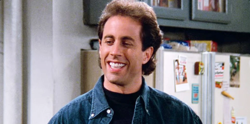 Comedian Jerry Seinfeld grinning in the show Seinfeld.