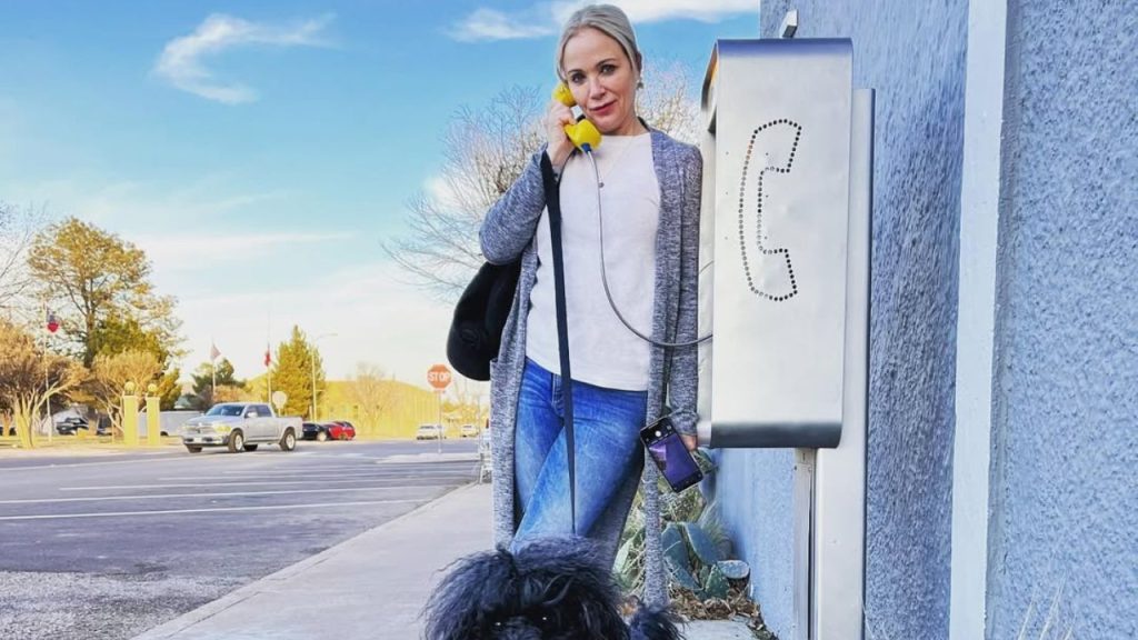 Lauren Holly posing for a picture at a telephone booth