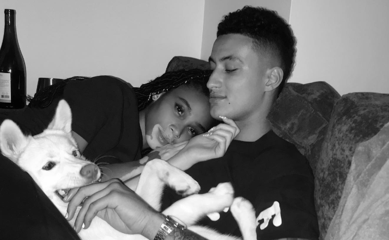 Winnie Harlow and Kyle Kuzma relaxing together in bed, sharing a cozy moment with their adorable dog. 