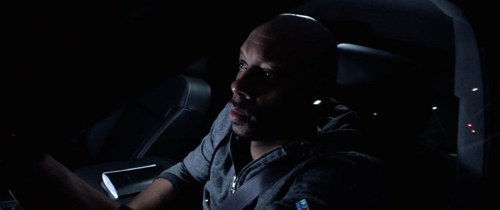 A dramatic low-light portrait of Dorian Missick in '9 Rides' in a car at night, illuminated by ambient lighting.